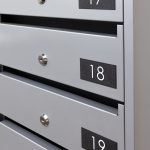 PD93_v4 sērijas iekštelpu daudzdzīvokļu nama pastkaste ar saliktām numerācijas plāksnītēm Nr. 17, 18 un 19, kur cipari ir balti un fons melns