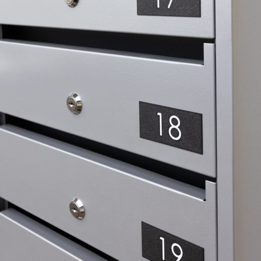 PD93_v4 sērijas iekštelpu daudzdzīvokļu nama pastkaste ar saliktām numerācijas plāksnītēm Nr. 17, 18 un 19, kur cipari ir balti un fons melns